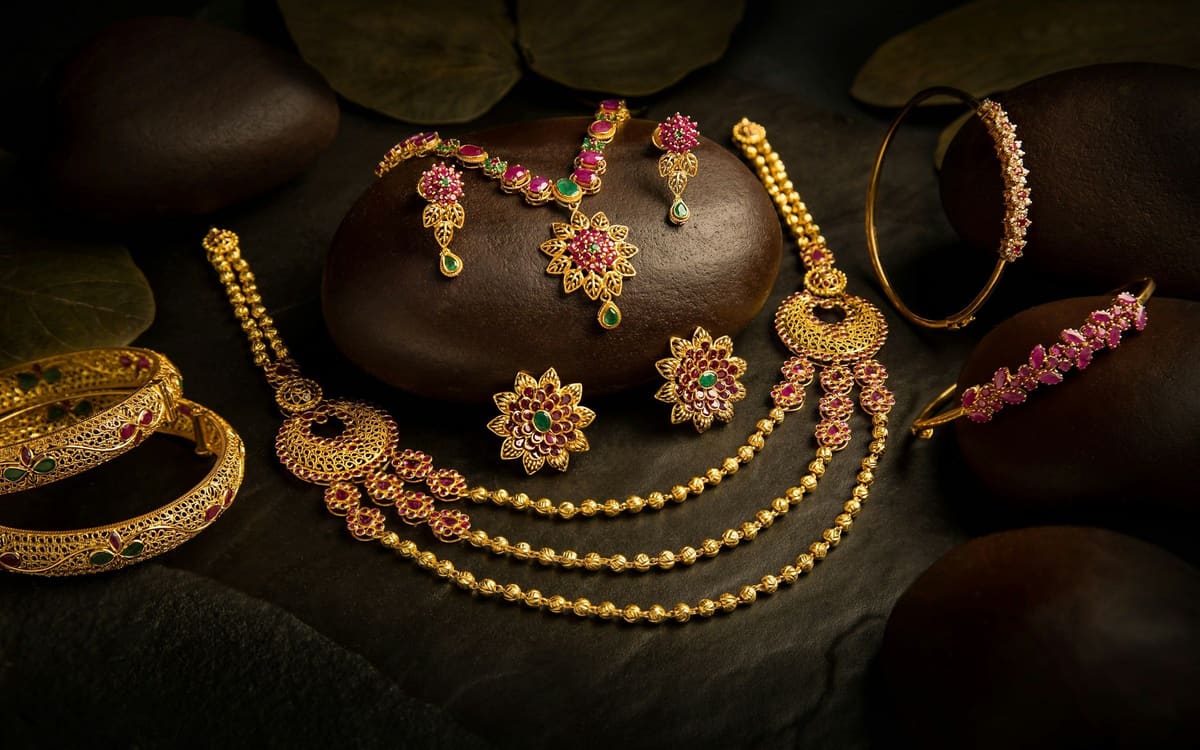Gold necklaces, earrings and bangles on dark stones