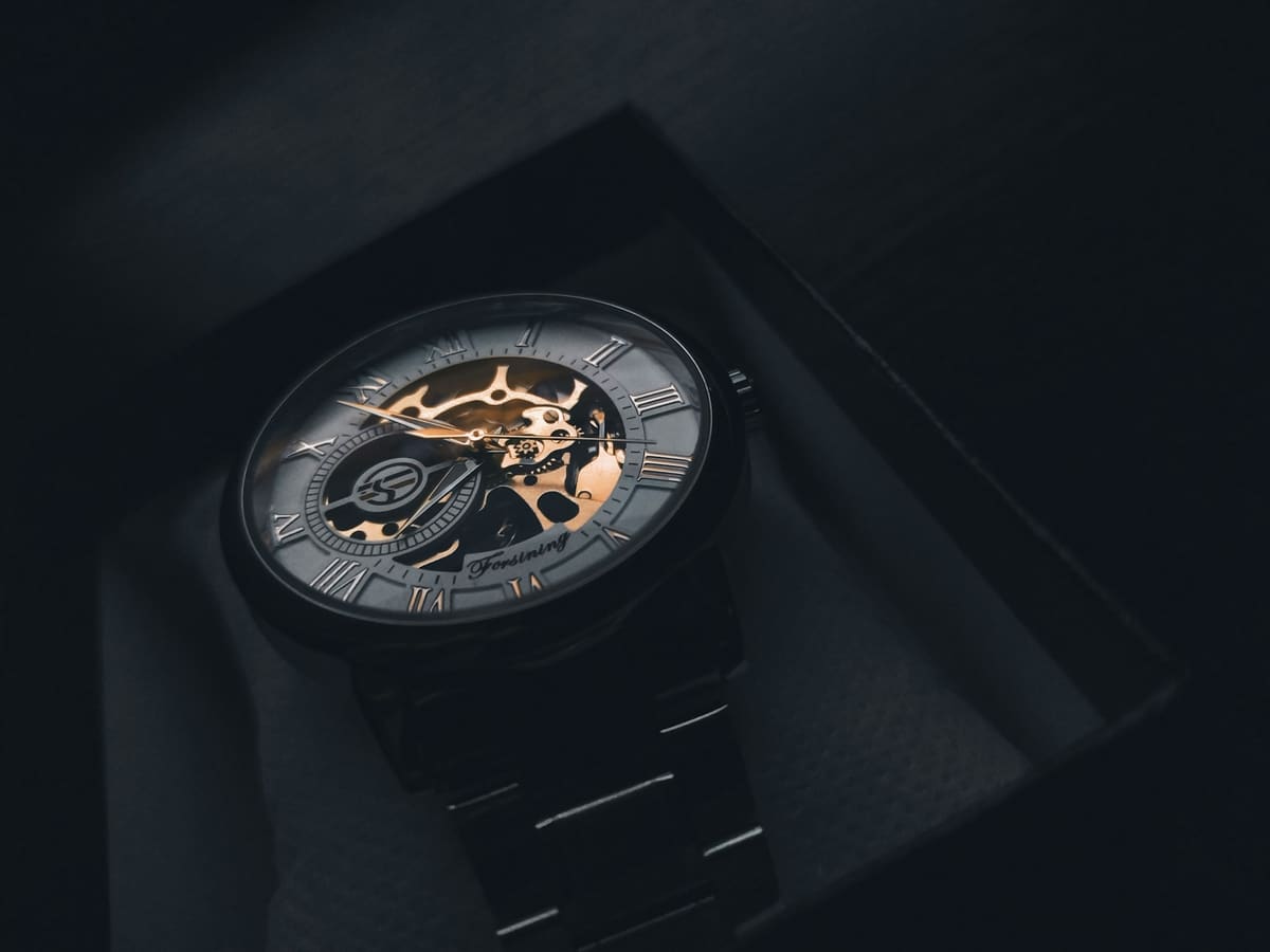 Reloj de pulsera de oro junto a un contrato y una pluma